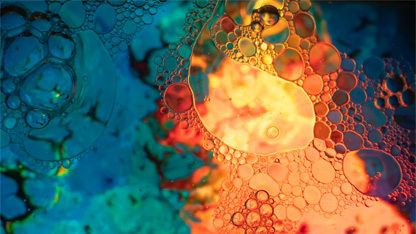 En makrobild på en emulsion av olja och vatten under starkt blått och orangt ljus